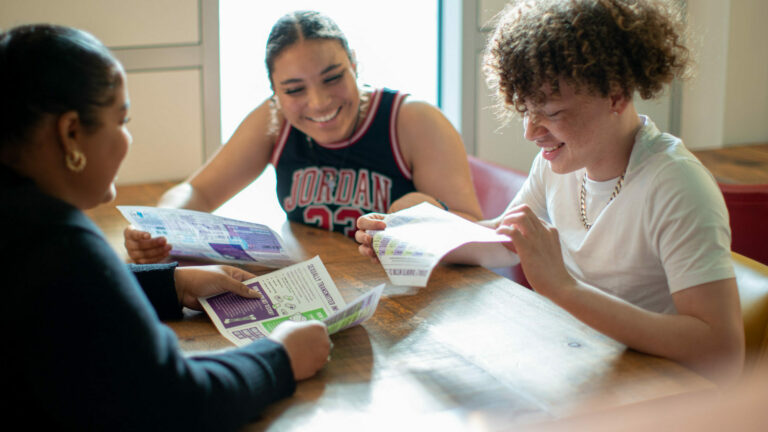 Three students sat round a table looking at activity sheets.